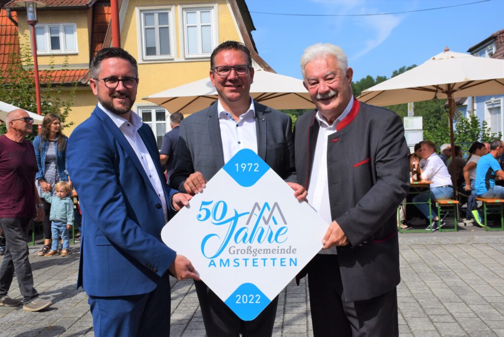 Gruppenbild von Ortsvorsteher Manuel Scherscher, Bürgermeister Christian Haberhauer, Ortsvorsteher a. D. Anton Ebner - sie halten die Tafel "50 Jahre Großgemeinde Amstetten" in den Händen