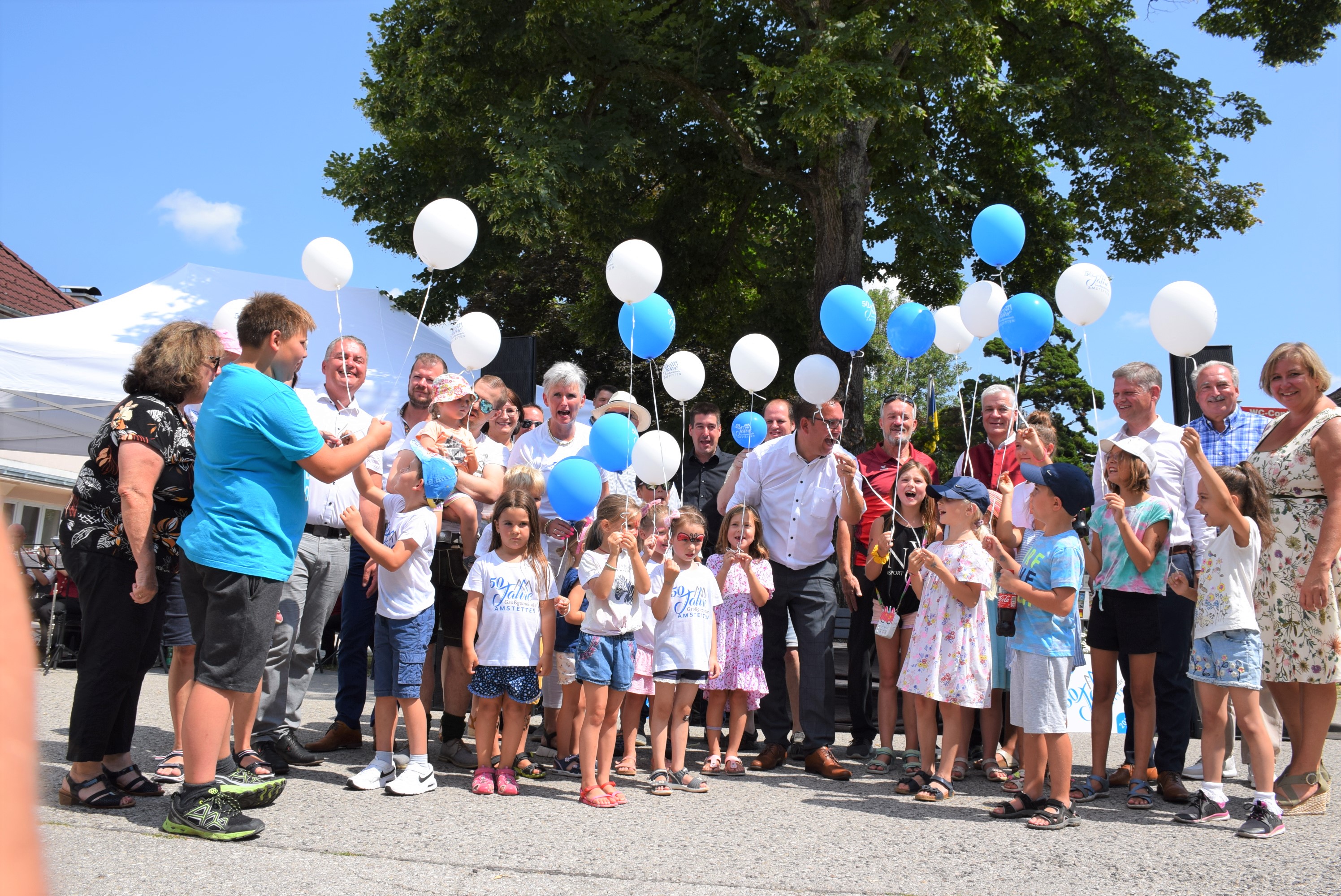 Bürgermeister Christian Haberhauer lässt mit Kindern Luftballone steigen.