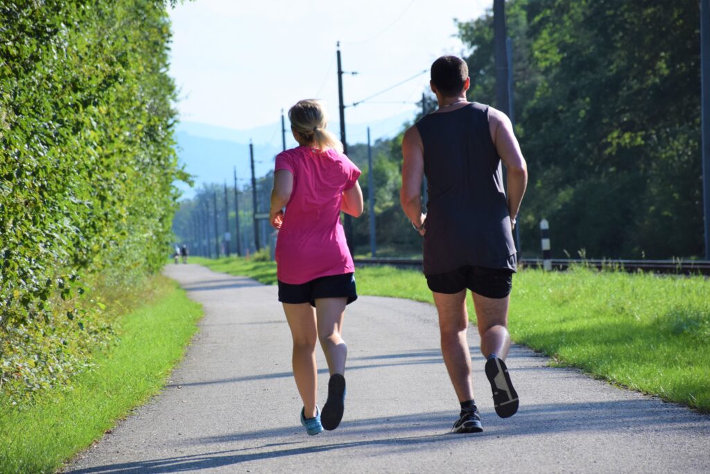 Zwei Menschen joggen entlang einer Bahnstrecke