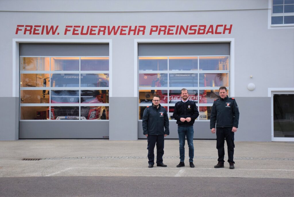Der Vorplatz der Freiwilligen Feuerwehr Preinsbach. Vor den Tor der Feuerwehr stehen Kommandant OBI Florian Tietze, Ortsvorsteher Andreas Gruber und Kommandant-Stv. BI Christian Schweighofer.