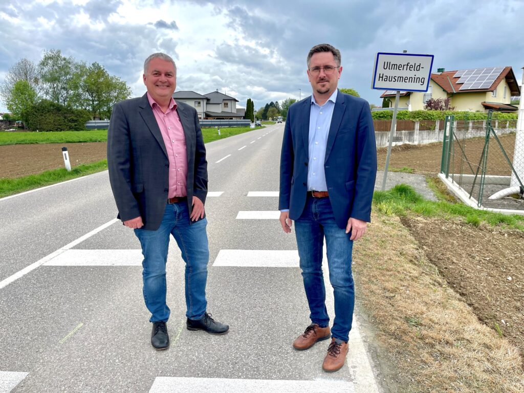 Ortsvorsteher Anton Geister und Ortsvorsteher Manuel Scherscher stehen bei der Ortseinfahrt von Ulmerfeld-Hausmening.